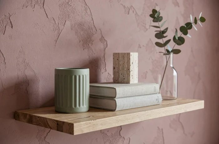 Vignette décorative tendance sur étagère minimaliste avec bougeoir en grès sauge, livres en lin et vase en verre pour sublimer un intérieur en 2024